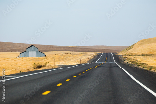 Foto Rural highway, country road, view of old barn and golden fields
