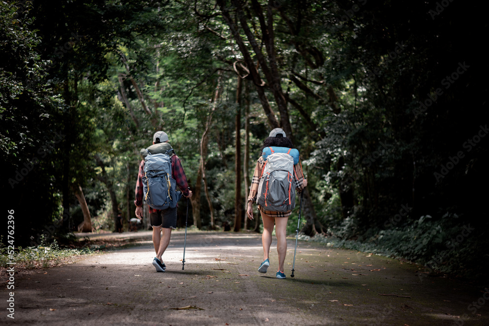 Fototapeta premium trekker tourist backpack ,hat with trekking stick . they show hold hand help adventure trekking at beautiful national park waterfall in summer vacation is eco tourism concept
