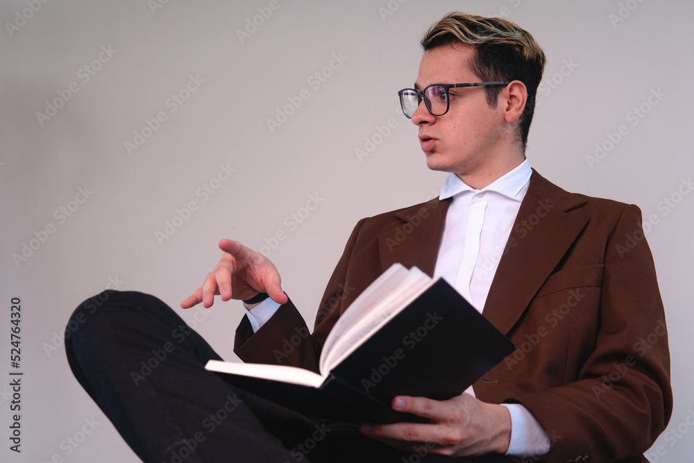 Lawyer sitting in front of a white background talking. Business man sitting with the black book on him. Teacher dressed in a suit presenting a topic. Elegant man dressed in jacket, shirt and glasses Lawyer sitting in front of a white background talking. Business man sitting with the black book on him. Teacher dressed in a suit presenting a topic. Elegant man dressed in jacket, shirt and glasses