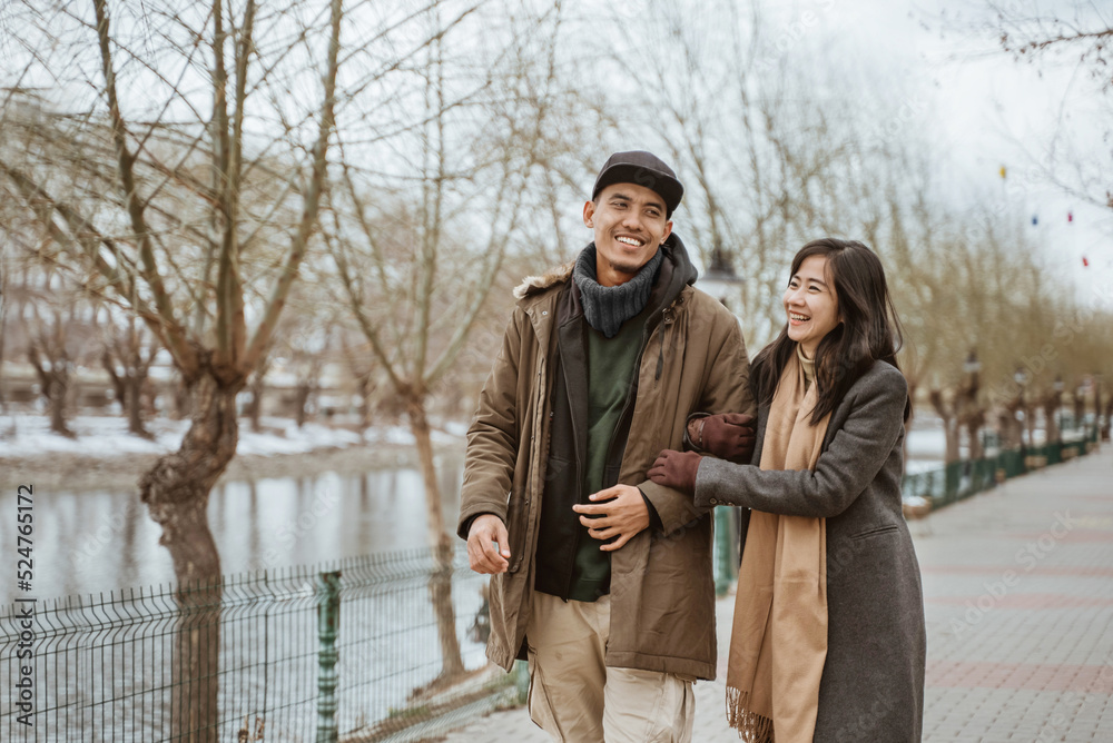 Obraz premium happy couple enjoying their time together walking near a river in winter