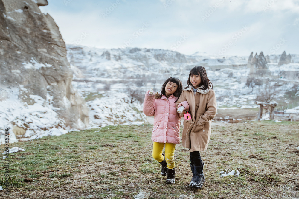 two little girl walking together and hold hand outdoor in the snow