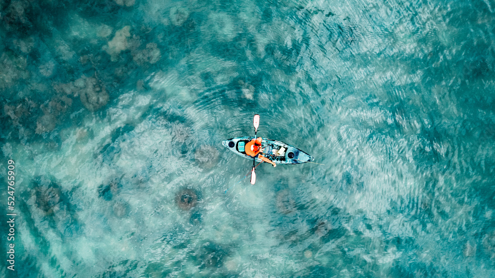 Fototapeta premium A man is seen fishing from a kayak near the shore