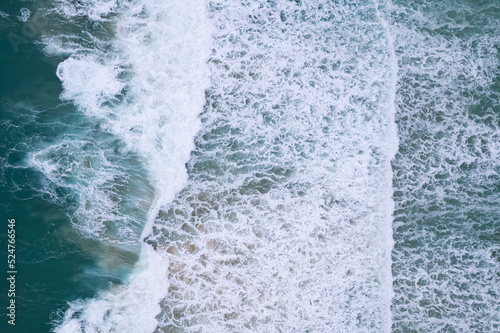 Dark sea surface aerial view.Top view blue water ocean waves with white foaming waves crashing on beach background. Amazing sea waves nature background