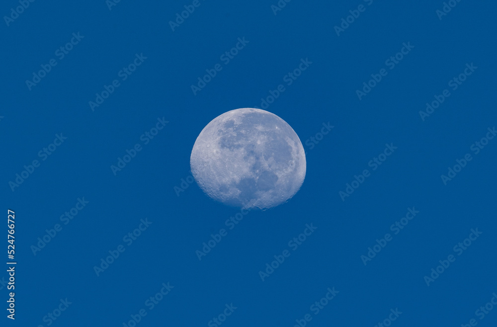 Full moon against blue sky background