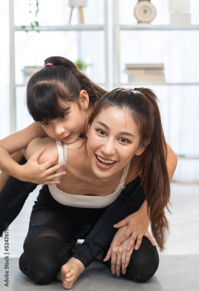 Asian young mother and her daughter setting prepare to yoga and meditation pose together on yoga mat in living room at home. Fitness lifestyle. Asian young mother and her daughter setting prepare to yoga and meditation pose together on yoga mat in living room at home. Fitness lifestyle.