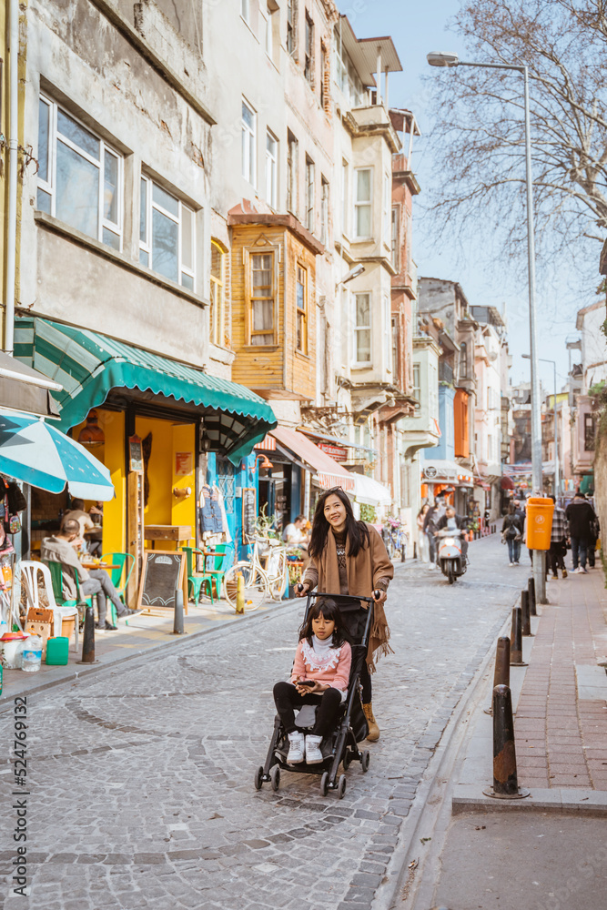 mother push her daughter on stroller while exploring city of istanbul
