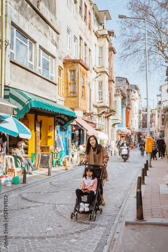mother push her daughter on stroller while exploring city of istanbul