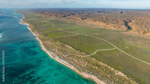 Areal view of the coastline in Cape Range National Park. The turquoise waters meeting the dry yet green bushland next to the rugged ridges of the range. © Mathias