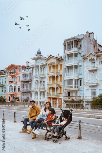 Photography portrait of asian family sitting on a bench with beautiful building at the backg