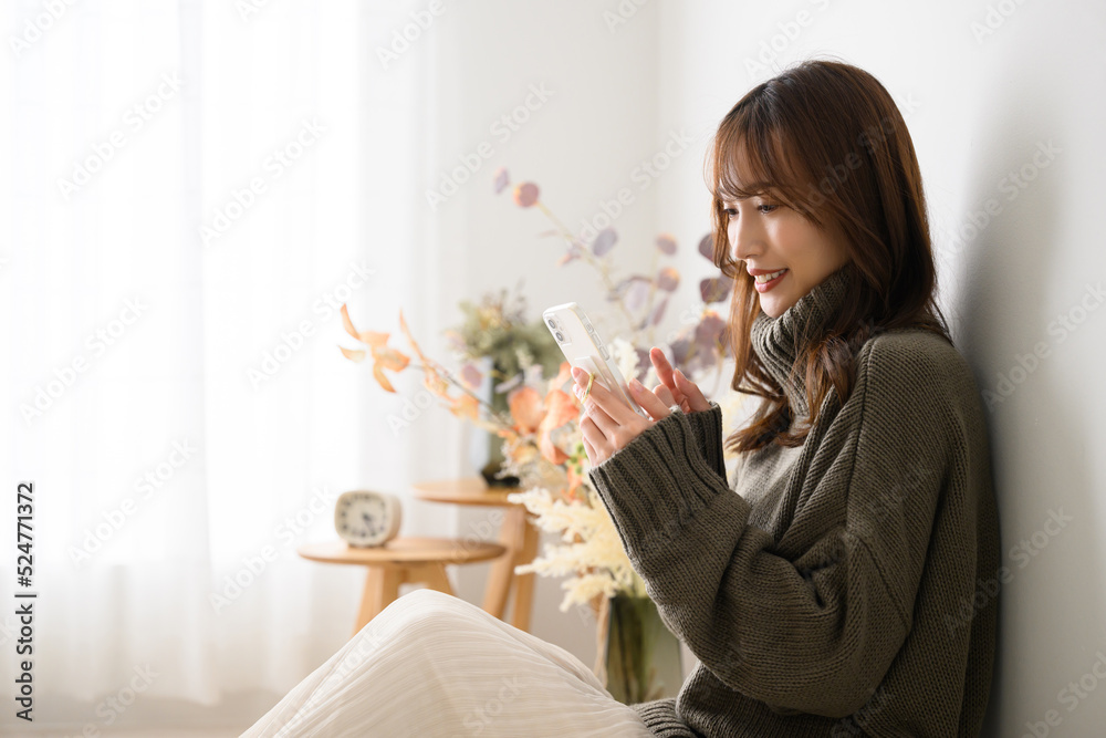 Japanese woman holding a cell phone, with space for copying Autumn/Winter knitwear Japanese woman holding a cell phone, with space for copying Autumn/Winter knitwear