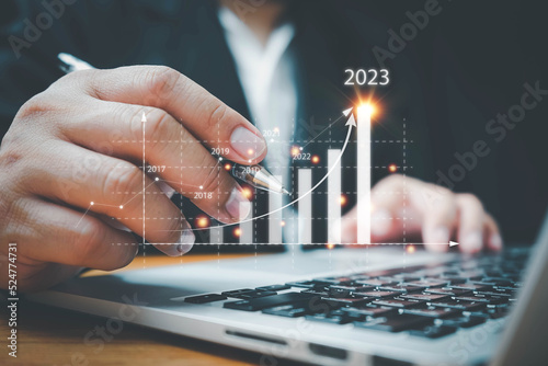 Businessman using computer analyzes the profitability of working companies with digital augmented reality graphics, positive indicators in 2023, a business calculates financial data for investments.