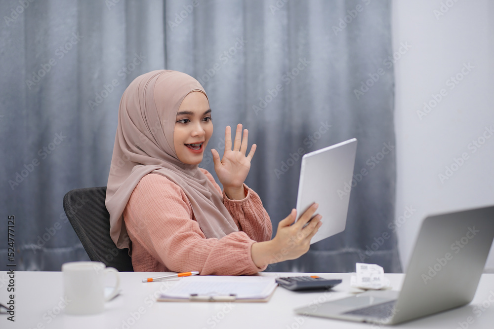 Beautiful asian muslim woman brown hijab having video call with friends or lover, using digital tablet at her home. Beautiful asian muslim woman brown hijab having video call with friends or lover, using digital tablet at her home.