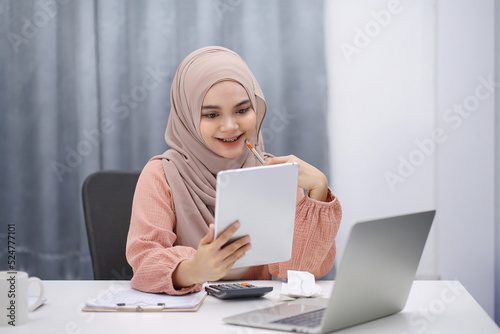 Beautiful asian muslim woman brown hijab having video call with friends or lover, using digital tablet at her home.