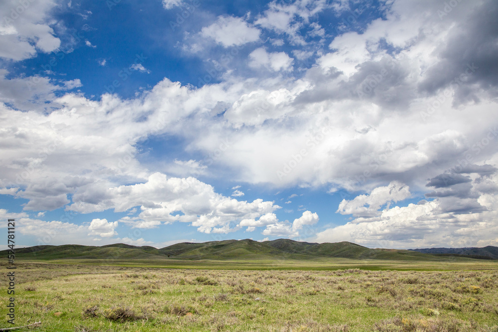 Partly cloudy sky over green plains and hills