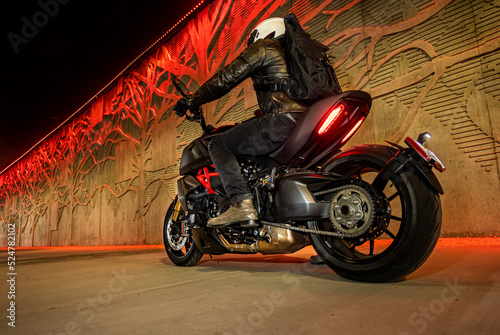 Man riding street motorcycle in a tunnel with a red light photo