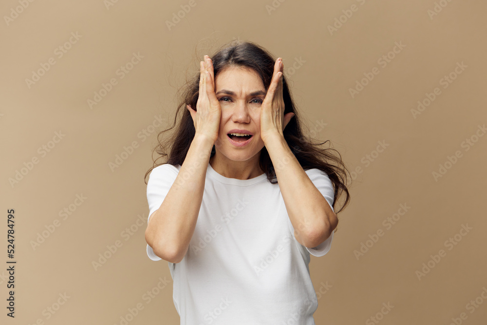 emotional, pleasant, funny woman with long well-groomed hair flying in the wind stands in a white T-shirt and shouts loudly holding her hands near her face emotional, pleasant, funny woman with long well-groomed hair flying in the wind stands in a white T-shirt and shouts loudly holding her hands near her face