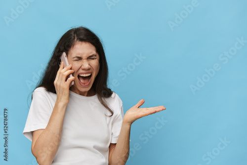 portrait of an emotional, screaming, surprised woman in a white t-shirt on a light blue background. Horizontal studio photo