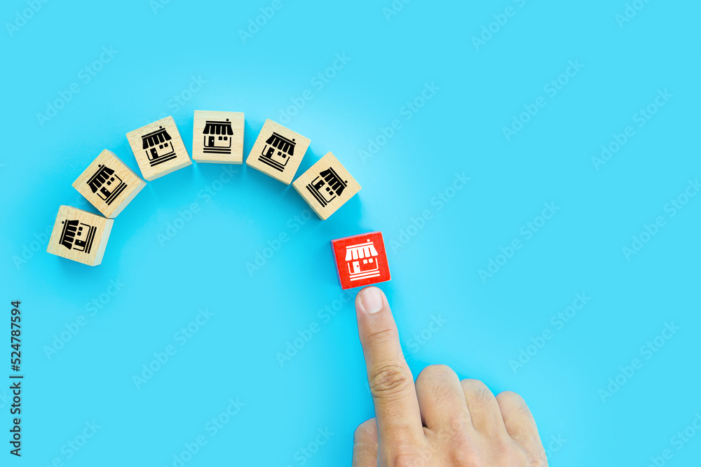 Fototapeta premium Franchise or franchising, Hand choose cube wooden toy block stack with franchises business store icon for growth and products services or branch expansion or bank loan.