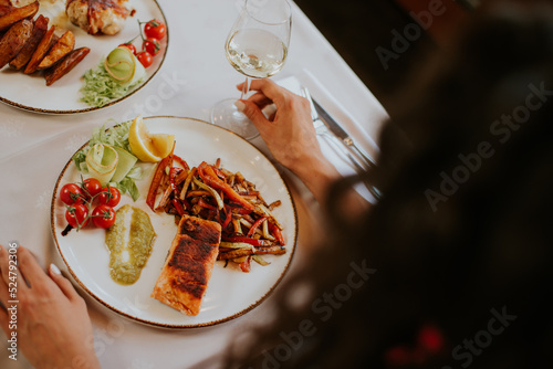 Fotografia Young couple having lunch with white wine in the restaurant