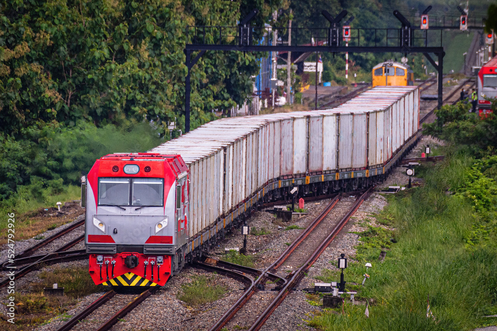Fototapeta premium Diesel locomotive towing a gray container.