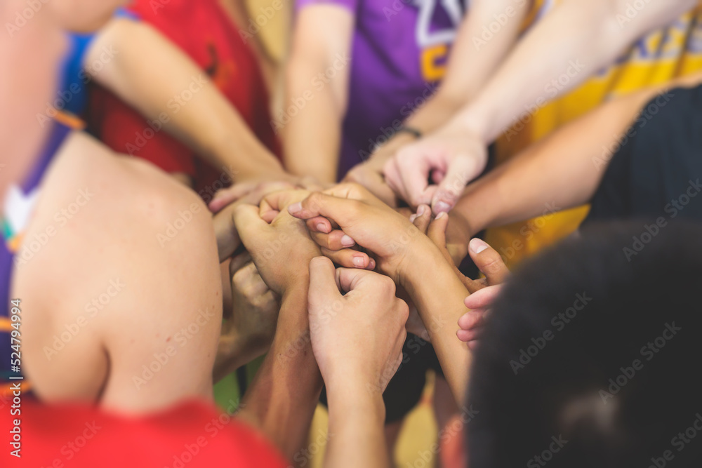 Obraz premium Team of kids children basketball players stacking hands in the court, sports team together holding hands getting ready for the game, playing indoor basketball, team talk with coach, close up of hands