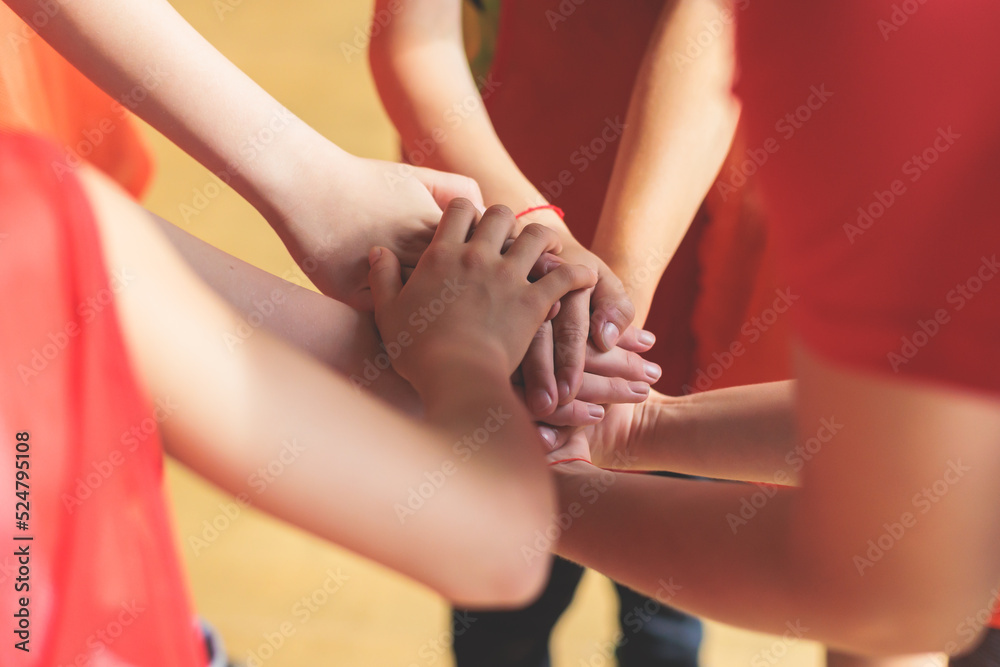 Team of kids children basketball players stacking hands in the court, sports team together holding hands getting ready for the game, playing indoor basketball, team talk with coach, close up of hands Team of kids children basketball players stacking hands in the court, sports team together holding hands getting ready for the game, playing indoor basketball, team talk with coach, close up of hands
