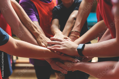 Team of kids children basketball players stacking hands in the court, sports team together holding hands getting ready for the game, playing indoor basketball, team talk with coach, close up of hands