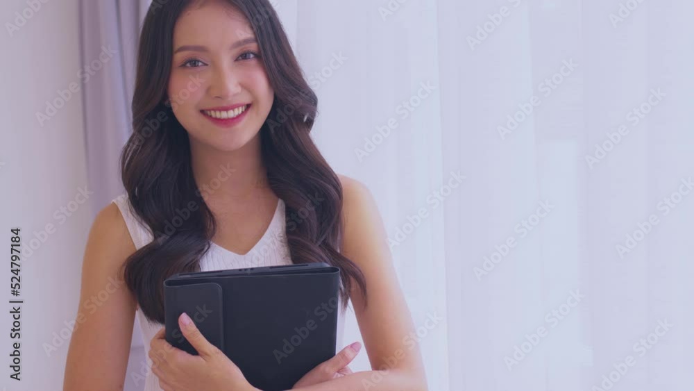 Asian woman standing and holding tablet for playing game and social media or chatting with her friends. Asian woman standing and holding tablet for playing game and social media or chatting with her friends.