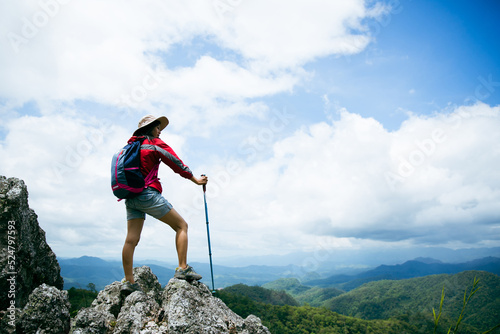 Young person hiking female standing on top rock, Backpack woman looking at beautiful mountain valley at sunlight in summer, Landscape with sport girl, high hills, forest, sky. Travel and tourism.