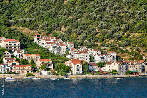 Kotor, Montenegro - July 18, 2022: Shoreline buildings and cathedrals along the narrow fjord en route to Kotor, Montenegro  © Torval Mork