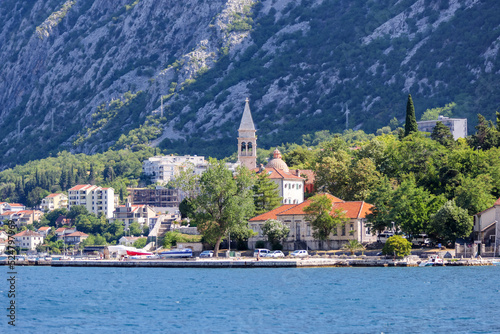 Kotor, Montenegro - July 18, 2022: Shoreline buildings and cathedrals along the narrow fjord en route to Kotor, Montenegro  © Torval Mork