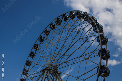 Large metal Ferris wheel close-up against a blue sky with white clouds in Vladimir russia © Inna