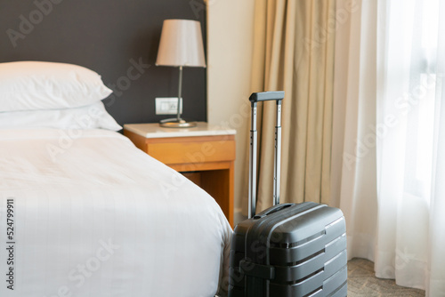 Black travel suitcase in bedroom or hotel room and window curtain background. Relaxing time on holidays, weekend and traveling, business trip concept. Copy space photo