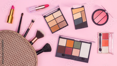 Make up products in cosmetics kit on pastel pink background. Flat lay