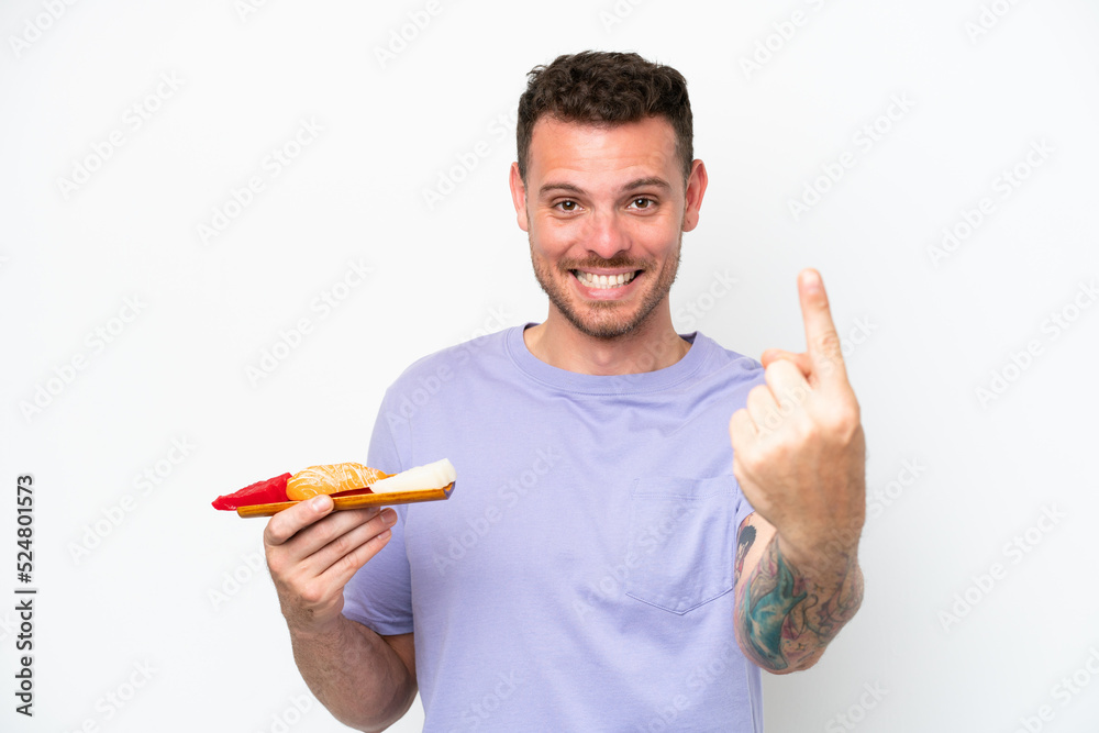 Young caucasian man holding sashimi isolated on white background doing coming gesture Young caucasian man holding sashimi isolated on white background doing coming gesture