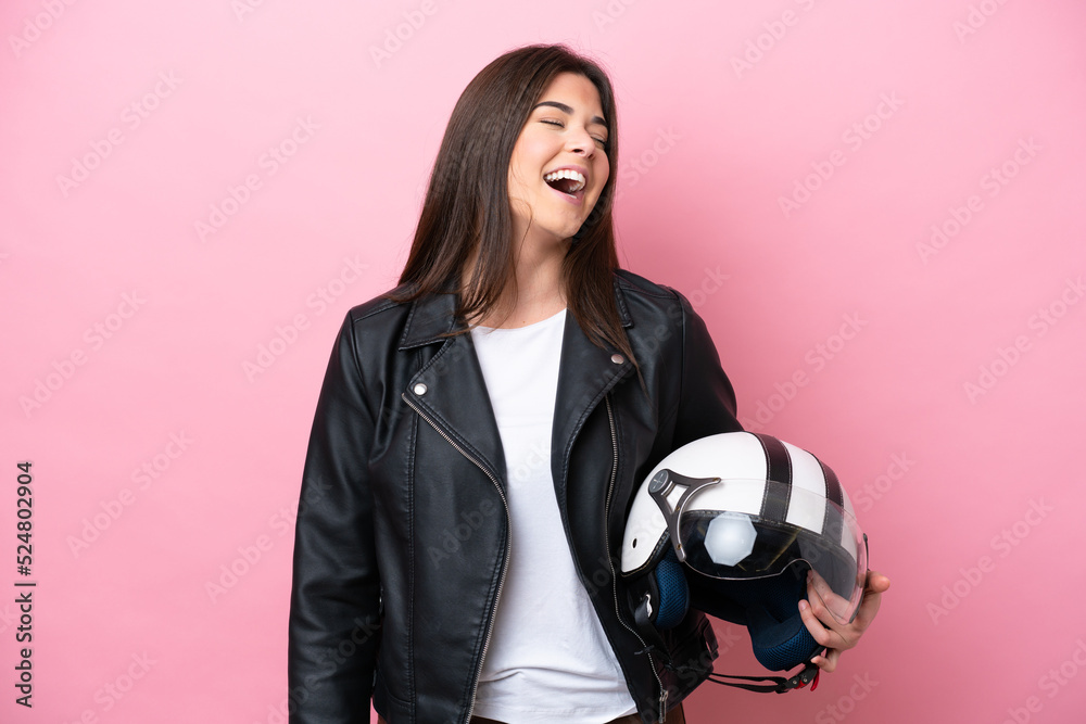 Young Brazilian woman with a motorcycle helmet isolated on pink background laughing Young Brazilian woman with a motorcycle helmet isolated on pink background laughing