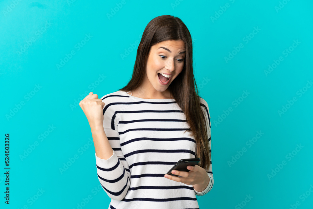 Teenager Brazilian girl over isolated blue background surprised and sending a message Teenager Brazilian girl over isolated blue background surprised and sending a message