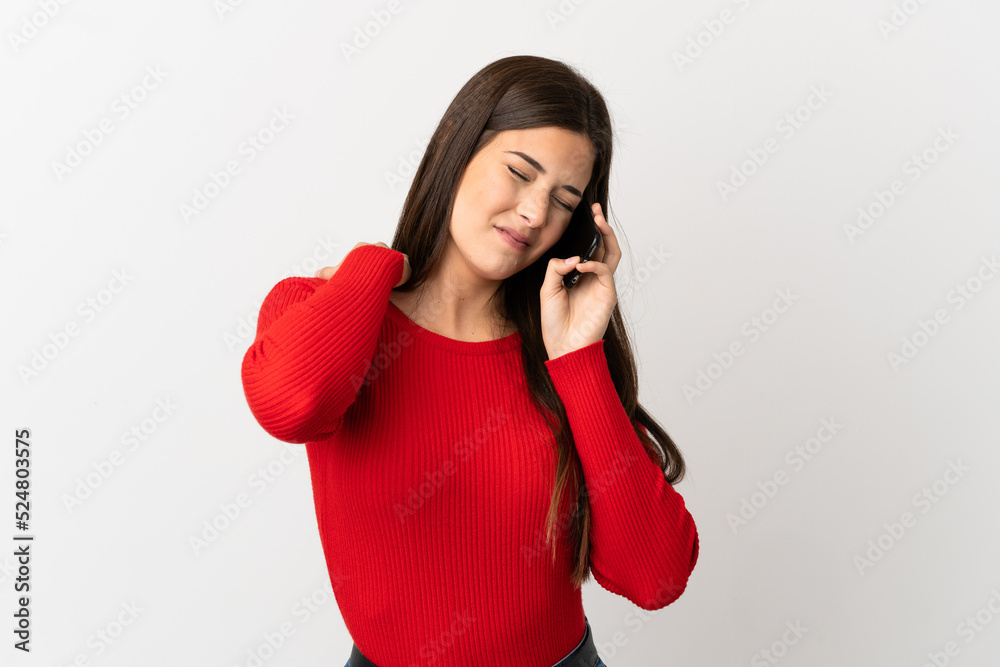 Teenager Brazilian girl using mobile phone over isolated white background suffering from pain in shoulder for having made an effort Teenager Brazilian girl using mobile phone over isolated white background suffering from pain in shoulder for having made an effort