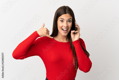 Teenager Brazilian girl using mobile phone over isolated white background making phone gesture. Call me back sign