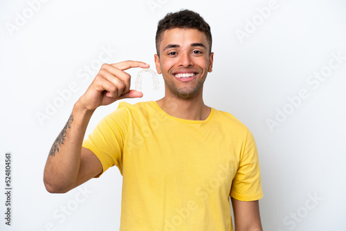 Young Brazilian man holding invisible braces isolated on white background with happy expression