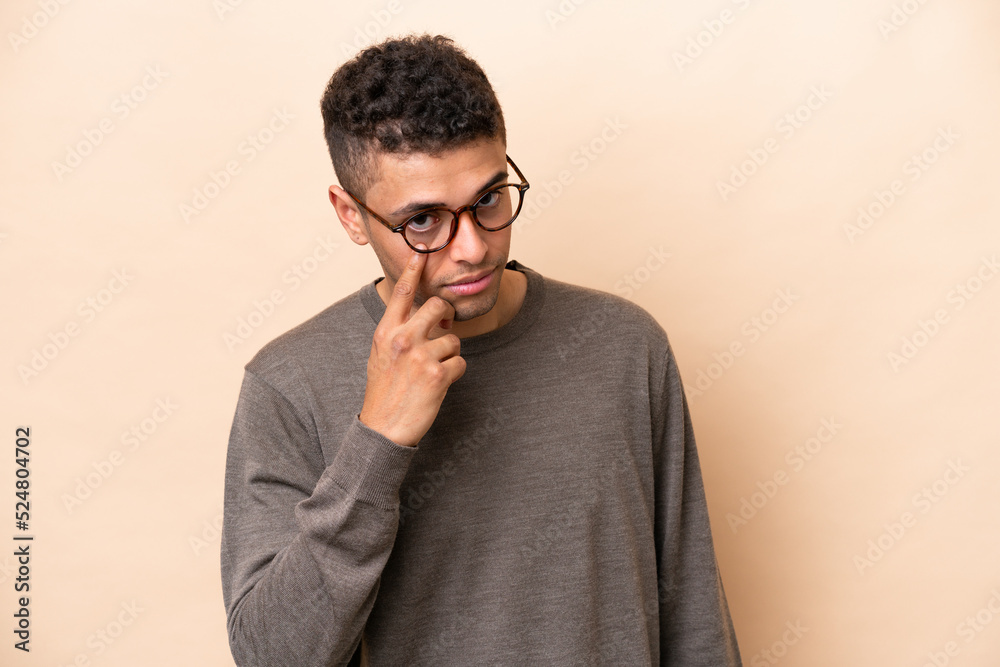 Young Brazilian man isolated on beige background showing something Young Brazilian man isolated on beige background showing something