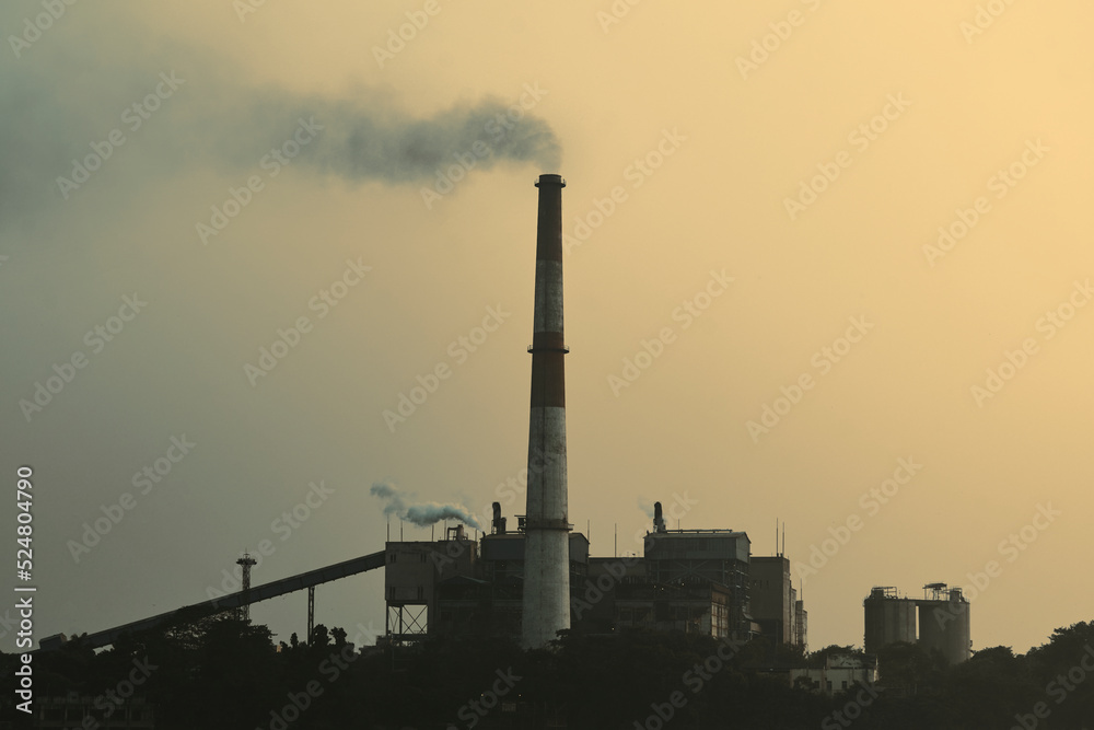 Factory chimney emitting smoke at a thermal power station beside Ganges river. Photo taken during dusk. Factory chimney emitting smoke at a thermal power station beside Ganges river. Photo taken during dusk.