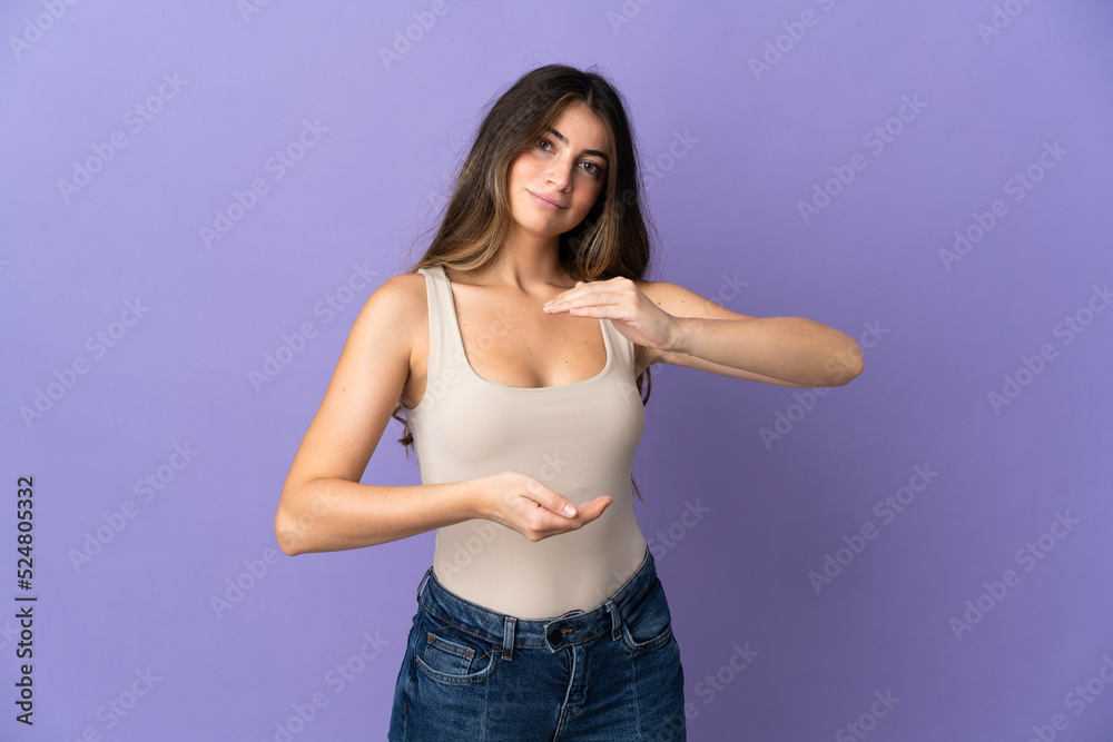 Young caucasian woman isolated on purple background holding copyspace imaginary on the palm to insert an ad Young caucasian woman isolated on purple background holding copyspace imaginary on the palm to insert an ad