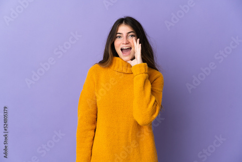 Young caucasian woman isolated on purple background shouting with mouth wide open © luismolinero
