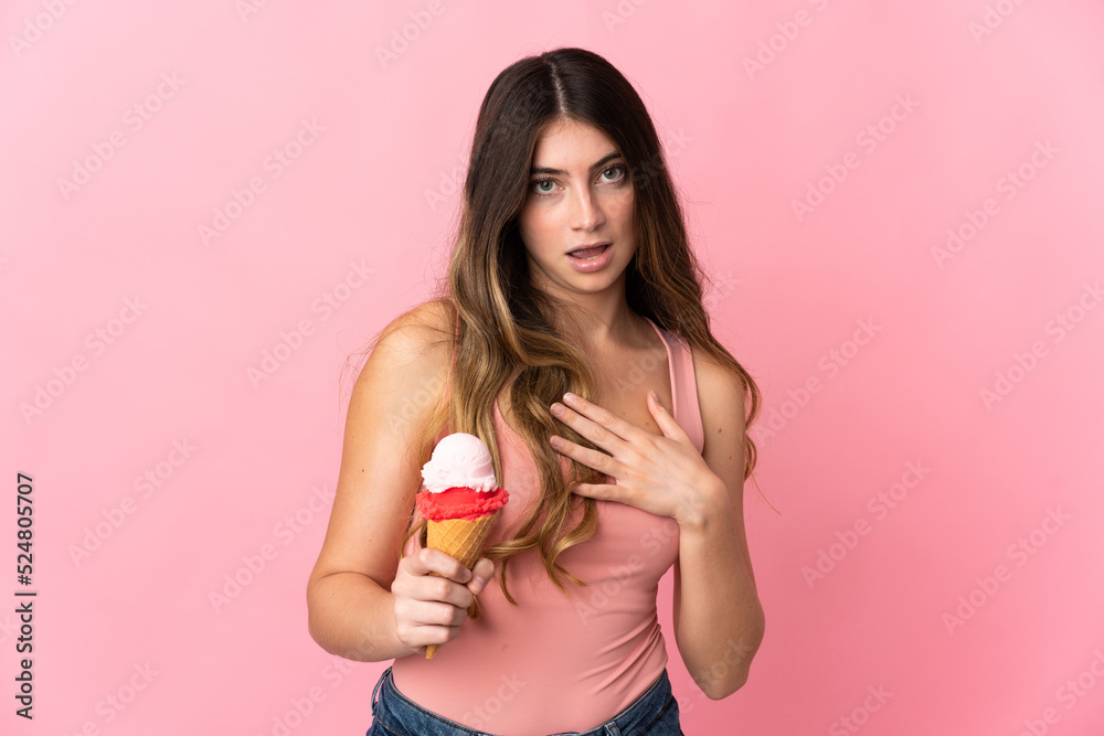 Young caucasian woman with a cornet ice cream isolated on pink background surprised and shocked while looking right Young caucasian woman with a cornet ice cream isolated on pink background surprised and shocked while looking right