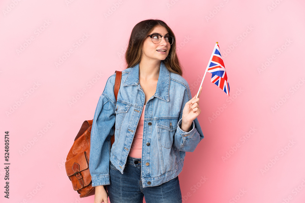 Young woman holding an United Kingdom flag isolated on pink background thinking an idea while looking up Young woman holding an United Kingdom flag isolated on pink background thinking an idea while looking up