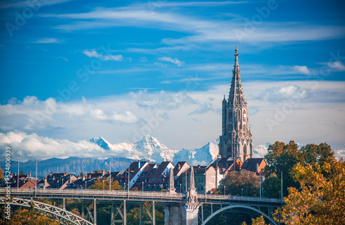 Scenic view of tower of Munster cathedral in Bern, Switzerland. Snowcaped alpine peaks on background. Picturesque sky. UNESCO World Heritage Site photo