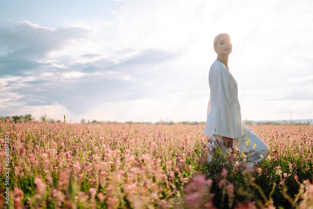 Young woman in stylish summer dress feeling free in the field with flowers. Nature, fashion, vacation and lifestyle