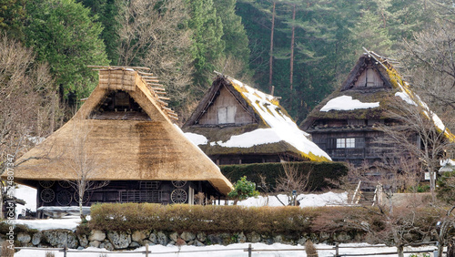 Old Japanese wooden house with thatched roof and remaining snow