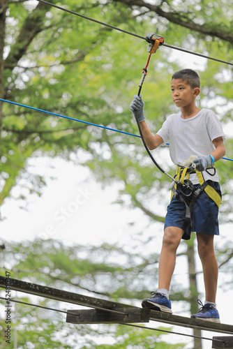 木の上のアスレチックで遊ぶ男子中学生 (12歳)